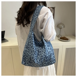 Detail of blue leopard print canvas tote bag showing texture and wide shoulder strap on model