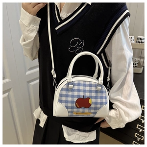 Detail of blue and white checkered mini bag with red apple pattern and white strap