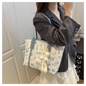 Détail du grand sac cabas en toile avec imprimés cartoon bleus et pendentif lapin