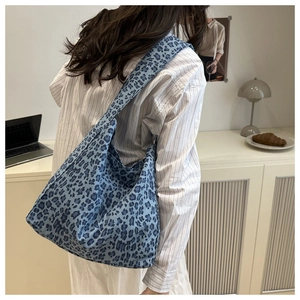 Detail shot of a blue leopard print canvas tote bag carried over the shoulder on a model
