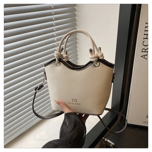 Detailed close-up of a two-tone bucket bag with knot handle and metal hardware