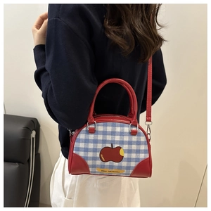 Detail showing checkered plaid Boston bag with red leather trim and apple print