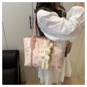 Détail d'un sac cabas blanc avec illustrations roses et breloque lapin en peluche sur un mannequin