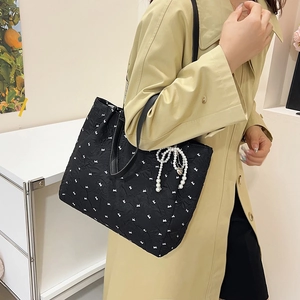 Sac fourre-tout noir matelassé avec motifs nœuds blancs et breloque perle sur la bandoulière