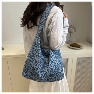 Blue leopard print canvas tote bag shown on model in a minimalist home setting