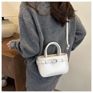 Détail du sac à main blanc cassé avec bandoulière réglable dans un intérieur chaleureux