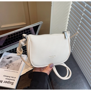 Detail view of white lychee leather bag featuring a knotted strap and embossed logo
