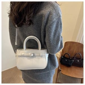 Trois sacs bandoulière carrés minimalistes en blanc, noir et marron sur une chaise en bois