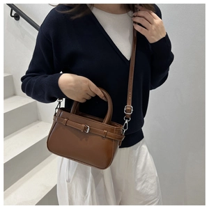 Détail du sac bandoulière en cuir mat marron avec boucle argentée et sangle amovible