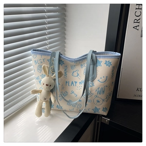 Gros plan du sac en toile avec graffiti bleu et porte-clés peluche lapin mignon suspendu