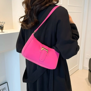 Sac à bandoulière rose fuchsia à fermoir en T doré porté par un mannequin chic