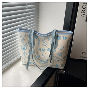 Détail du sac cabas en toile avec imprimés graffiti bleus et finitions en cuir lisse