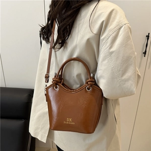 Brown leather bucket bag with top handles and adjustable strap by DX Do&thinks