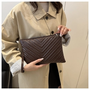 Close-up of V-quilted dark brown clutch with metallic studs and leather wrist strap