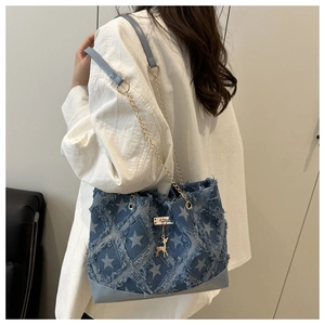 Détail du sac cabas en denim bleu avec étoiles blanches et pendentif cerf doré sur modèle