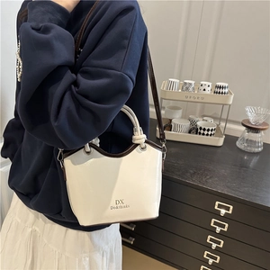Minimalist beige bucket shoulder bag with brown leather straps and metal hardware