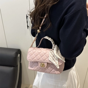 Pink quilted crossbody bag with scarf-wrapped handle and gold chain strap on a model