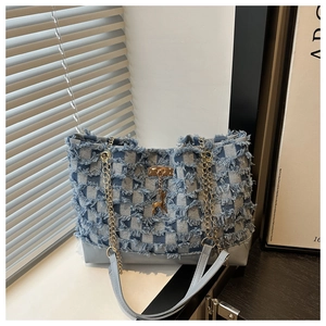 Détail du sac cabas en jean bleu avec coutures à carreaux effilochés et pendentif