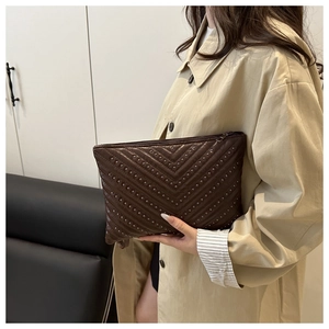 Close-up of retro dark brown envelope bag featuring V-shaped stud texture and zipper