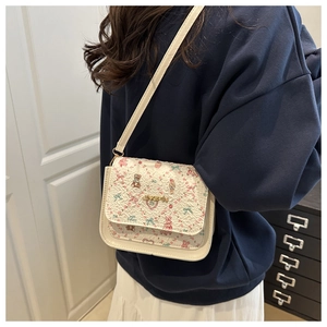 Close-up of white crossbody bag with cute strawberry bear prints and golden logo