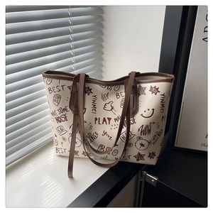 Détail du sac cabas crème à motifs graffiti avec bandoulière marron et étoiles