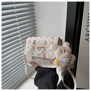 Detail of white square crossbody bag with pink floral patterns and plush rabbit accessory