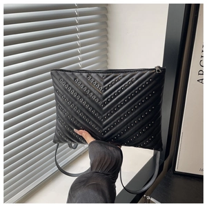Close-up of black chevron quilted leather bag with silver stud accents and zipper