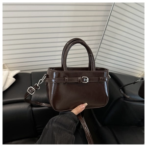 Détail d'un sac à main rétro en cuir brillant café foncé avec boucle décorative élégante