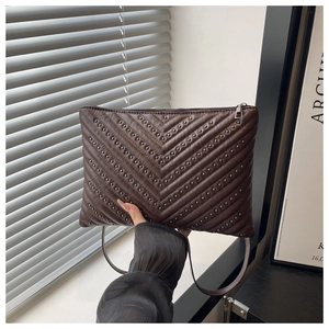 Detail of dark brown quilted bag with silver rivets in a stylish V-shape pattern