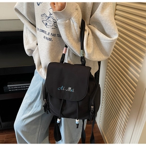 Detail of black nylon backpack featuring Ai Mei embroidery and drawstring closure