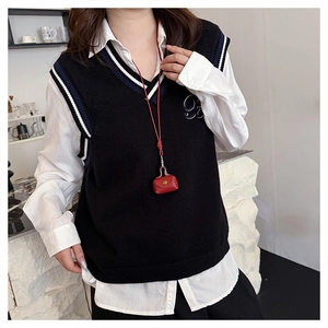 Close-up of minimalist black V-neck knitted vest with contrast stripes and number embroidery