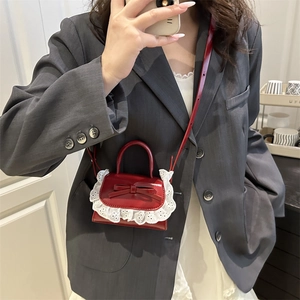 Mini borsa a tracolla in vernice rossa con fiocco e pizzo bianco sulla modella