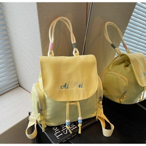 Detail of yellow nylon backpack with drawstring closure, flap cover, and bead accents