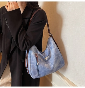 Detail of hobo shoulder bag with metal logo and dark brown straps on a model