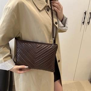 Vintage dark brown crossbody bag with V-shaped metal studs shown on a model