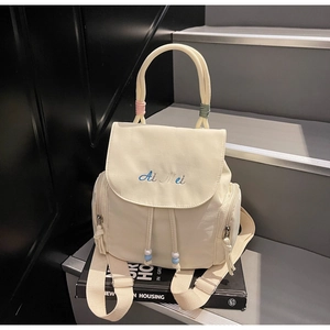 Detail of cream drawstring backpack with blue Ai Mei embroidery on a modern staircase