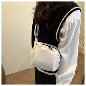 Vue détaillée d'un sac bandoulière blanc minimaliste en nylon porté pour un look décontracté