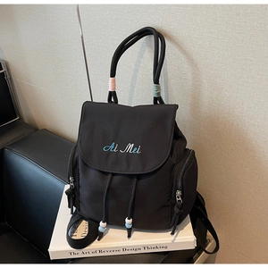 Close-up of black nylon backpack with Ai Mei embroidery and colorful drawstring beads