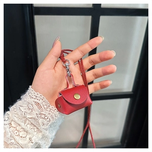 Close-up of red lychee leather mini square bag with gold stud buckle and woven lanyard