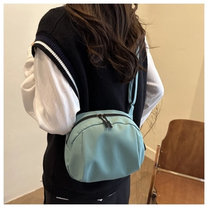 Détail du sac bandoulière bleu clair porté par un mannequin montrant taille et nylon