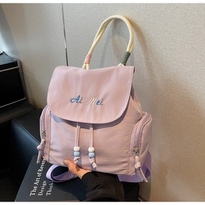 Detail of lavender nylon backpack featuring drawstring closure and bead tassel accents