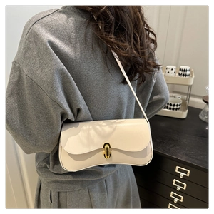 Detail of cream white leather underarm bag with gold twist lock on a model's shoulder