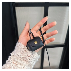 Macro detail of black litchi grain leather mini bag with gold buckle and lanyard