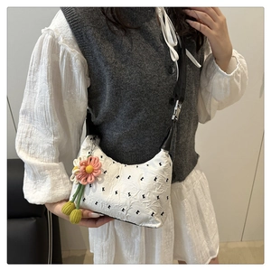 Detail of white pleated shoulder bag with black 'k' print and floral charm on model
