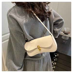 Close-up of a white minimalist shoulder bag featuring a sleek gold bar metal clasp