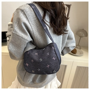 Detailed view of a navy denim hobo bag featuring pink and white bow embroidery