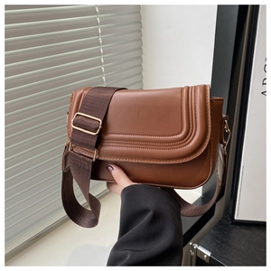 Dettaglio borsa a sella in pelle PU marrone con cuciture curve e tracolla larga