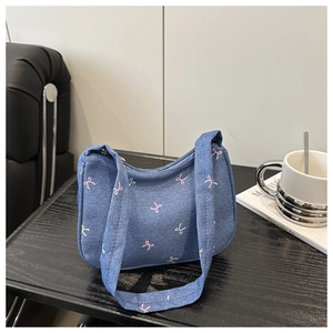 Detail of hobo shoulder bag featuring blue denim texture and pink bow patterns