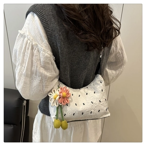 Detail of white quilted handbag with floral pendant on a shoulder bag for women