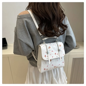 Détail d'un mini sac à dos blanc en similicuir avec motifs de chien et cerises mignons